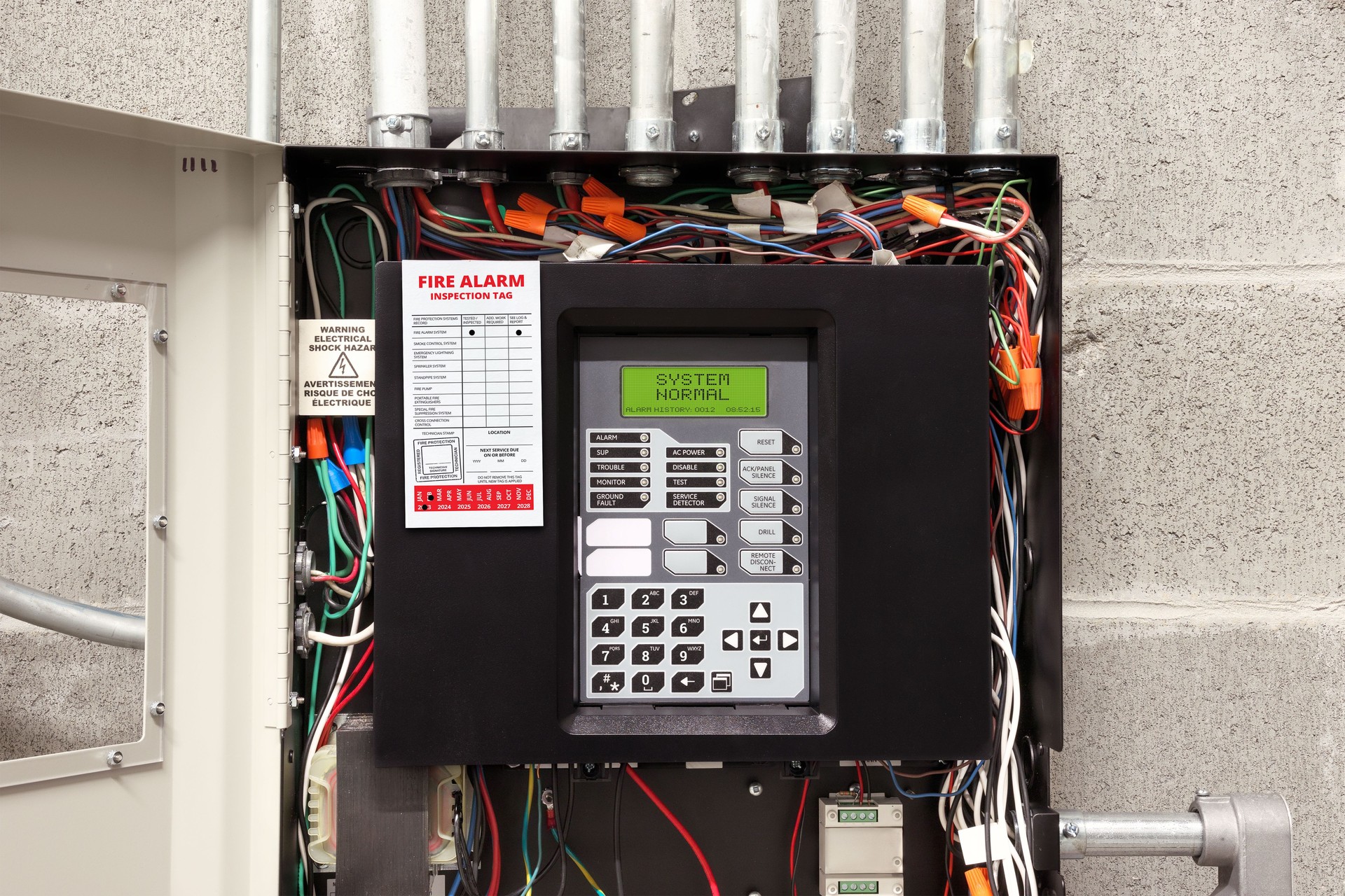 Fire alarm control panel in service room with fire inspection tag.